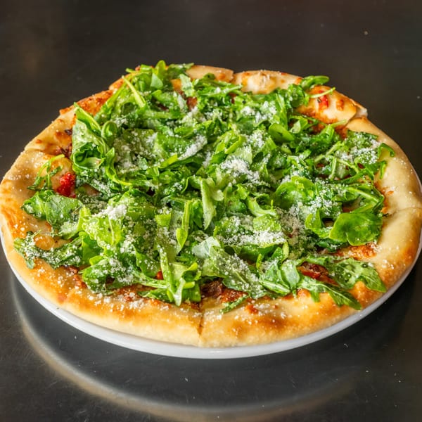 Arugula BLT pizza topped with fresh arugula and shaved parmesan.
