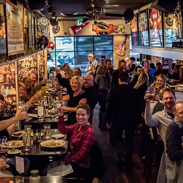 Dozens of happy customers raising glasses in a lively, memorabilia-filled restaurant and bar.