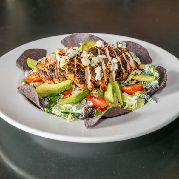 Blackened chicken salad with avocado, tomato, blue cheese, and blue corn tortilla chips.